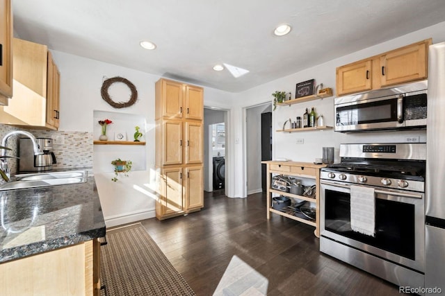 kitchen featuring sink, backsplash, dark stone counters, stainless steel appliances, and dark wood-type flooring