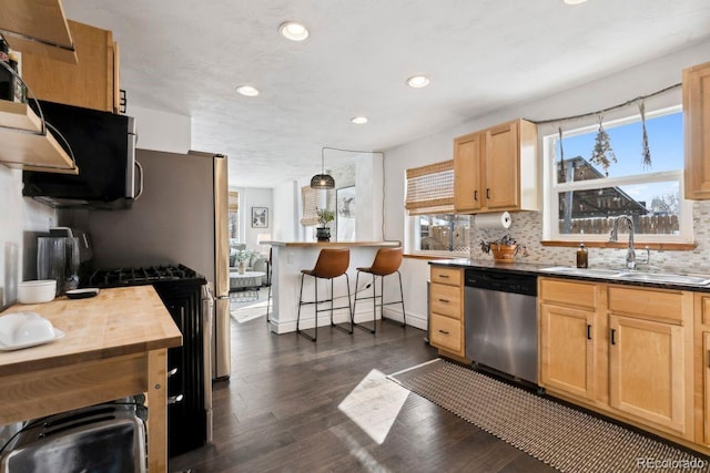 kitchen with a sink, light brown cabinets, stainless steel appliances, and recessed lighting