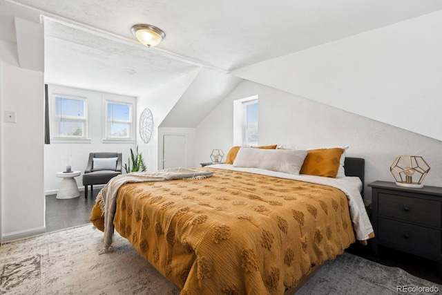 bedroom with baseboards, wood finished floors, and lofted ceiling