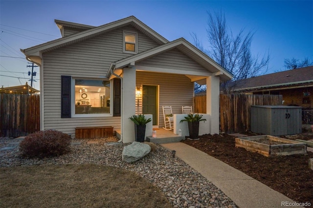 bungalow with a porch, fence, and a vegetable garden