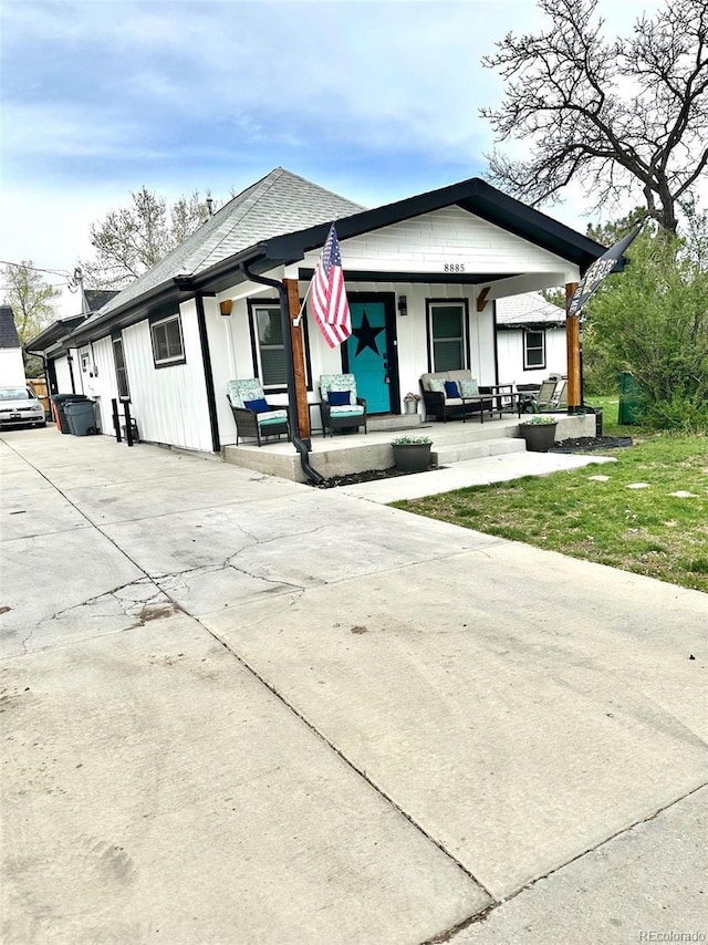 8885 W 64th Pl, Arvada, CO 80004 - bungalow with board and batten siding, roof with shingles, covered porch, and driveway