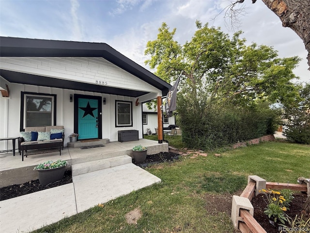 8885 W 64th Pl, Arvada, CO 80004 - view of front of house with board and batten siding, an outdoor living space, a front lawn, and covered porch