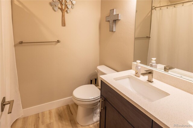 bathroom featuring toilet, vanity, and hardwood / wood-style flooring