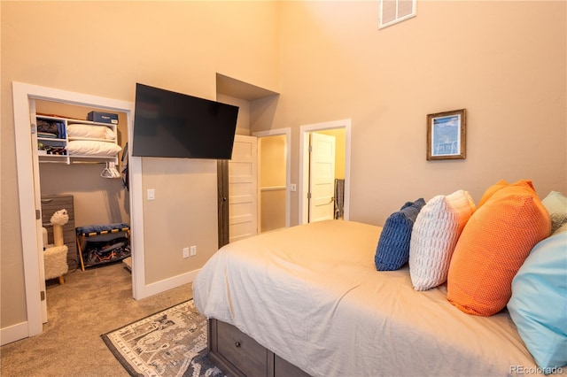 carpeted bedroom featuring a towering ceiling and a closet