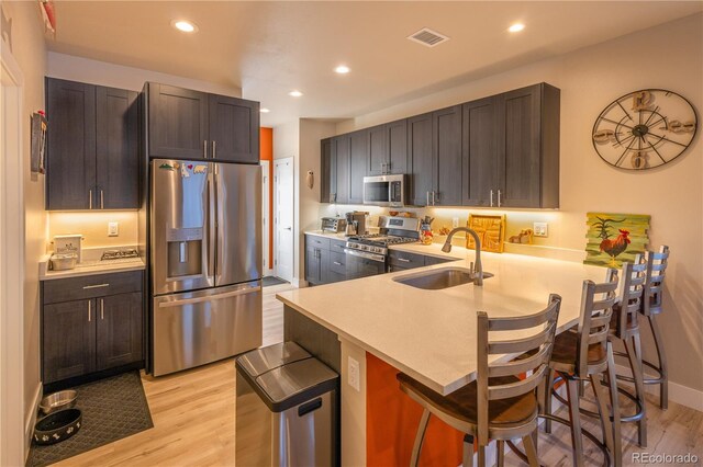 kitchen featuring sink, light hardwood / wood-style flooring, kitchen peninsula, a breakfast bar area, and appliances with stainless steel finishes