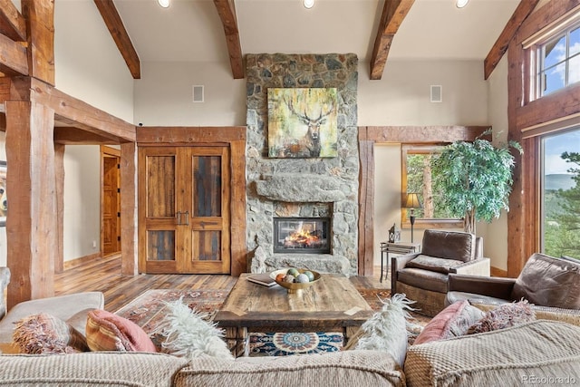 2929 Highlands View Rd, Evergreen, CO 80439 - living area featuring a high ceiling, beamed ceiling, wood finished floors, a stone fireplace, and recessed lighting