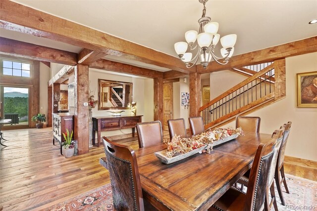 2929 Highlands View Rd, Evergreen, CO 80439 - dining space featuring a chandelier, light wood-style flooring, beam ceiling, and stairs
