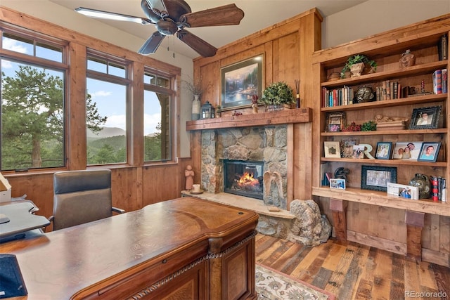 2929 Highlands View Rd, Evergreen, CO 80439 - office featuring wood finished floors, a ceiling fan, a fireplace, built in shelves, and wooden walls
