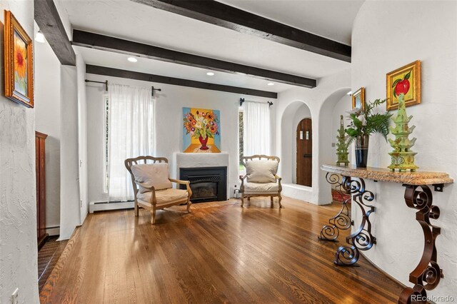 50 Albion St, Denver, CO 80220 - sitting room with a glass covered fireplace, arched walkways, wood finished floors, beam ceiling, and a baseboard radiator