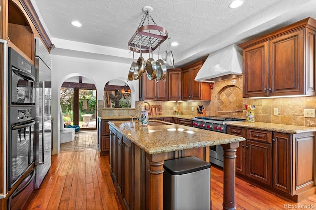 50 Albion St, Denver, CO 80220 - kitchen featuring high end stove, premium range hood, wood-type flooring, light stone countertops, and recessed lighting