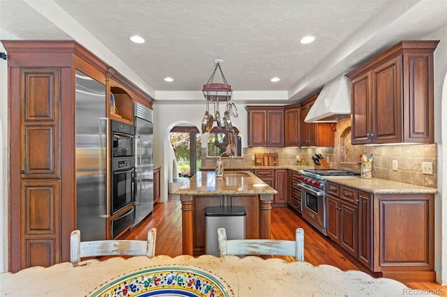 50 Albion St, Denver, CO 80220 - kitchen with high end appliances, custom range hood, dark wood-style floors, a kitchen island with sink, and light stone countertops