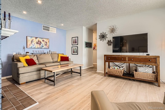 living area with wood finished floors, a textured ceiling, visible vents, recessed lighting, and baseboards