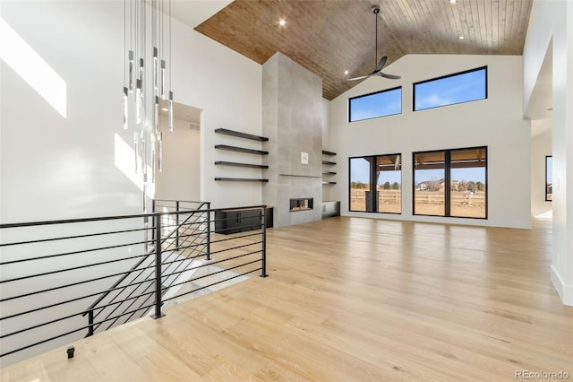 living room with wood ceiling, a fireplace, high vaulted ceiling, and light hardwood / wood-style flooring