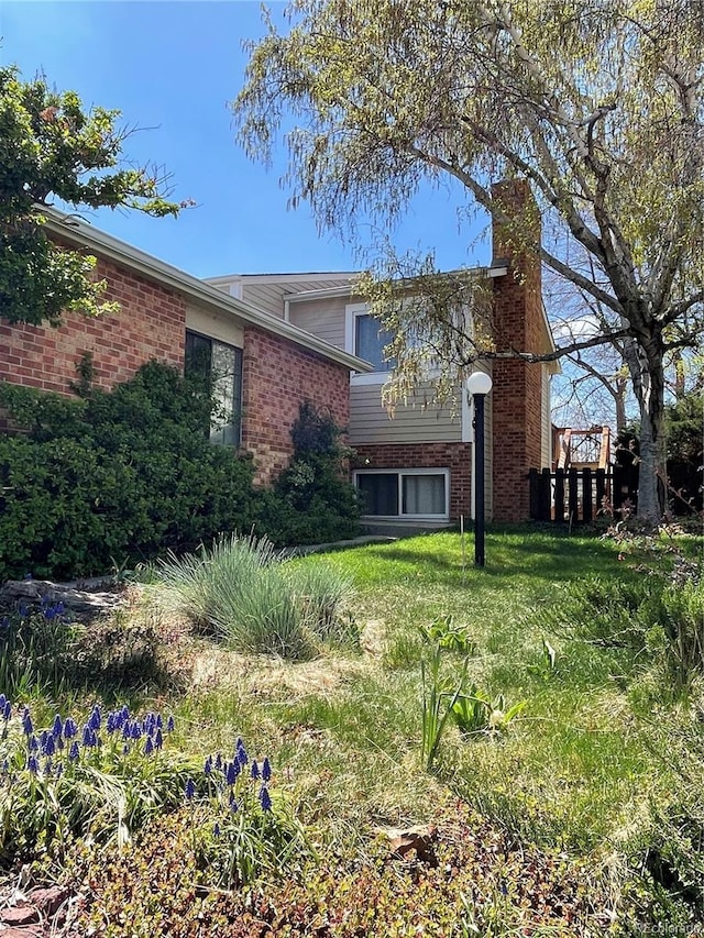 exterior space with brick siding, a front yard, and a chimney