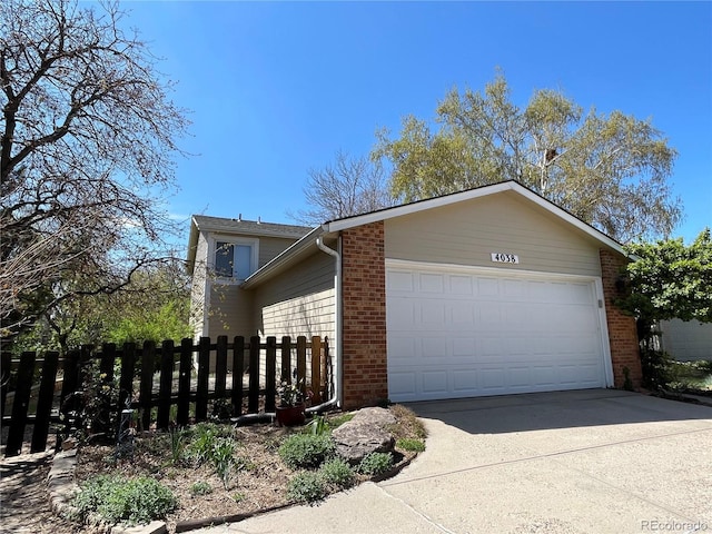 view of side of property featuring fence, an attached garage, brick siding, and concrete driveway