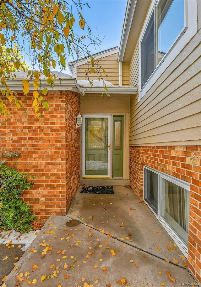 entrance to property featuring brick siding and a patio