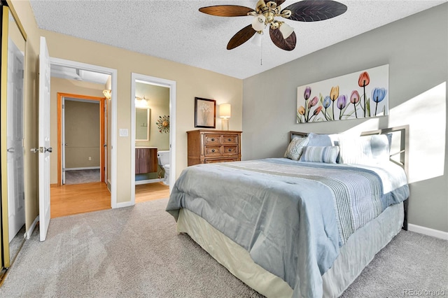 bedroom featuring ensuite bath, carpet floors, a textured ceiling, and baseboards