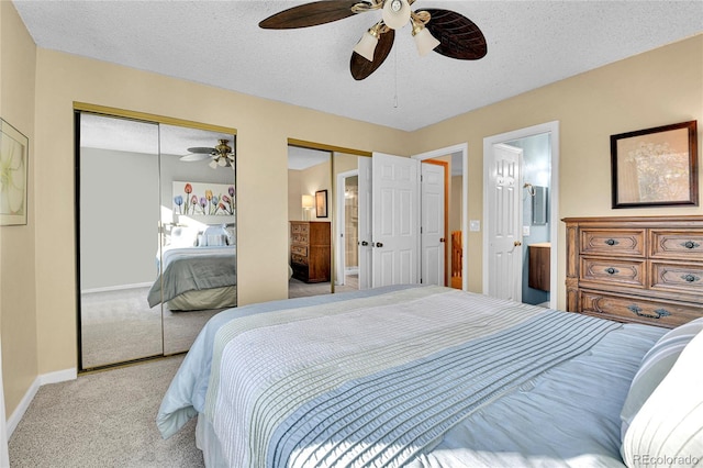 bedroom featuring carpet flooring, a textured ceiling, baseboards, a ceiling fan, and multiple closets