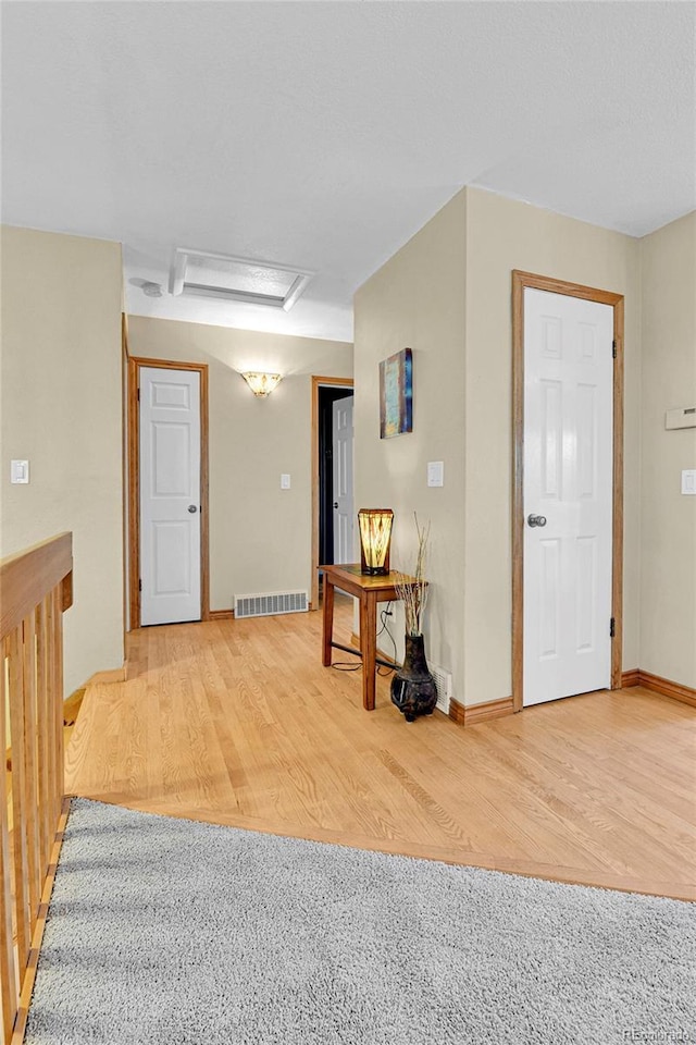 empty room with attic access, baseboards, wood finished floors, and visible vents