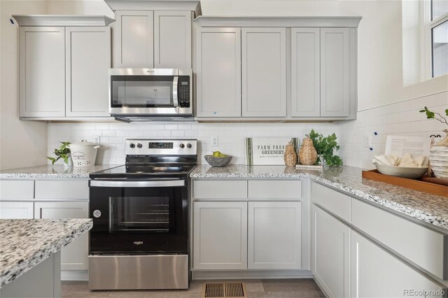 9865 Biscay St, Commerce City, CO 80022 - kitchen with stainless steel appliances, light stone counters, and backsplash