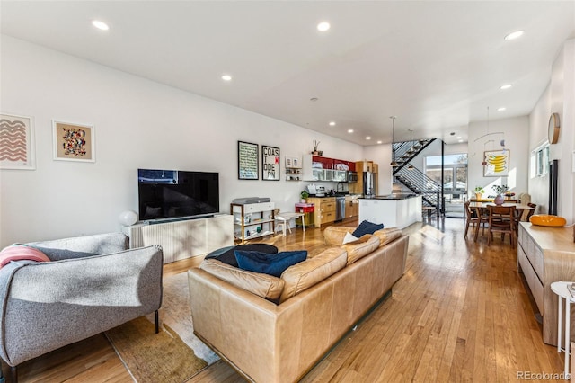 living room featuring light wood finished floors, stairway, and recessed lighting