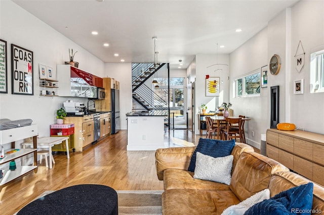 living room with recessed lighting, baseboards, light wood-style flooring, and stairs