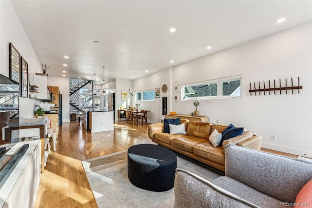 living room with recessed lighting, wood finished floors, and stairs