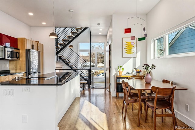 kitchen with stainless steel microwave, dark countertops, refrigerator, light wood finished floors, and baseboards