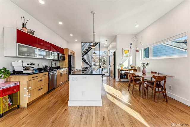 kitchen with dark countertops, a kitchen island, recessed lighting, light wood-style floors, and appliances with stainless steel finishes