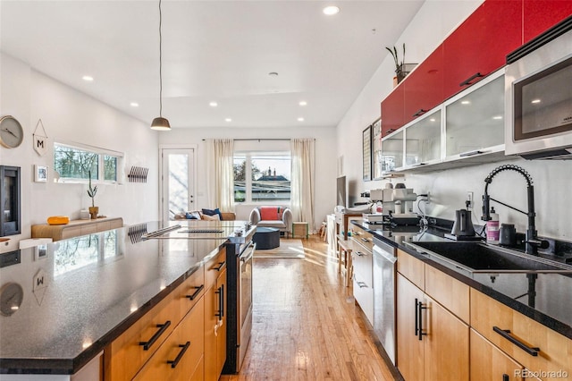 kitchen with a wealth of natural light, light wood-style flooring, stainless steel appliances, and a sink