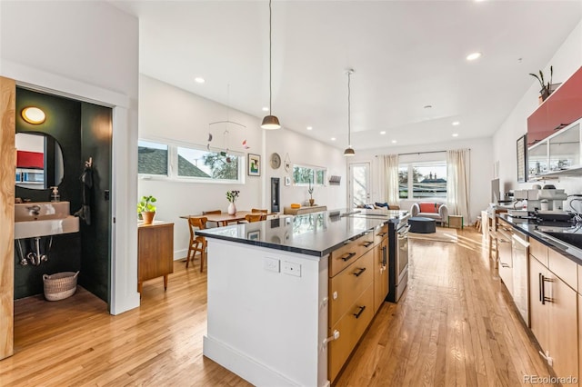 kitchen with light wood-style floors, stainless steel range oven, and dark countertops