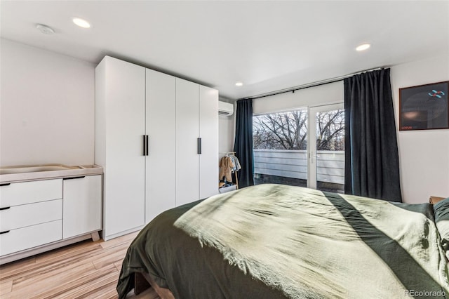 bedroom with recessed lighting, a wall mounted AC, and light wood-type flooring