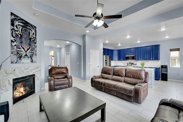 6829 Juniper Ct, Frederick, CO 80530 - living room with arched walkways, a ceiling fan, a high end fireplace, recessed lighting, and light tile patterned floors