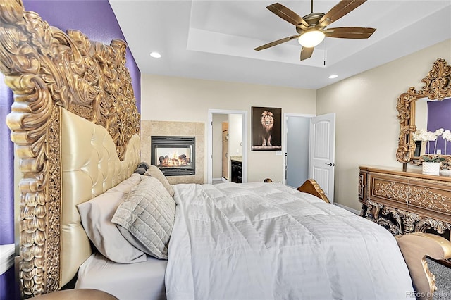 6829 Juniper Ct, Frederick, CO 80530 - bedroom featuring a raised ceiling, a fireplace, recessed lighting, ensuite bathroom, and a ceiling fan