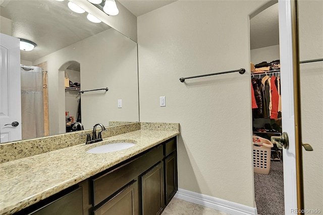 6829 Juniper Ct, Frederick, CO 80530 - full bath featuring vanity, a walk in closet, tile patterned flooring, and baseboards