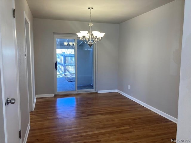 unfurnished dining area featuring an inviting chandelier, baseboards, and wood finished floors