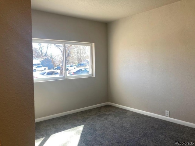 empty room with baseboards and dark carpet