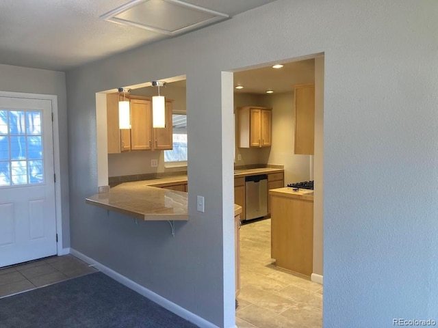 kitchen with baseboards, dishwasher, decorative light fixtures, a peninsula, and a kitchen bar