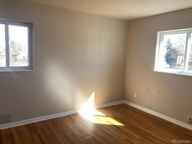 spare room with visible vents, baseboards, and wood finished floors