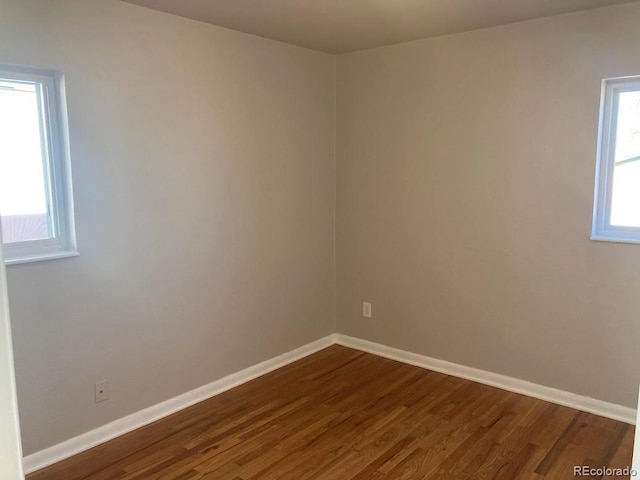 empty room featuring dark wood-type flooring and baseboards