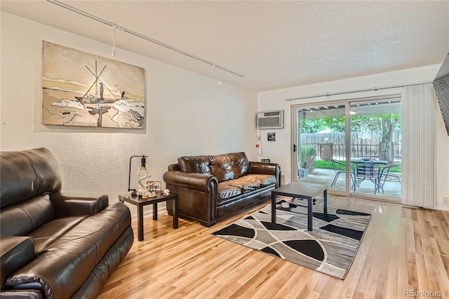 living room featuring hardwood / wood-style floors, a wall mounted air conditioner, rail lighting, and a textured ceiling