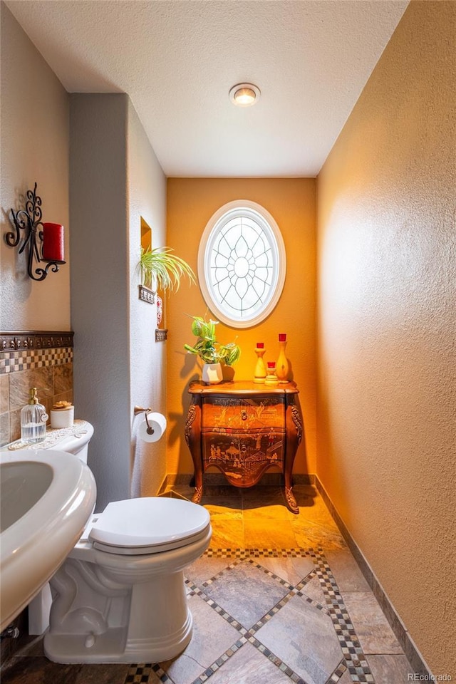 10218 Woodrose Ct, Highlands Ranch, CO 80129 - bathroom featuring toilet, a textured wall, baseboards, and a textured ceiling