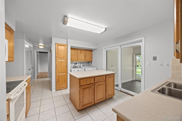 kitchen with electric range, washing machine and clothes dryer, a sink, and light tile patterned floors