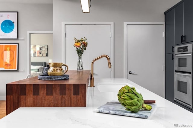 interior space with a sink, dark cabinets, and stainless steel double oven