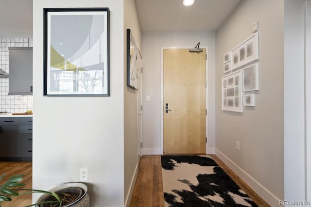 doorway to outside featuring baseboards and wood finished floors