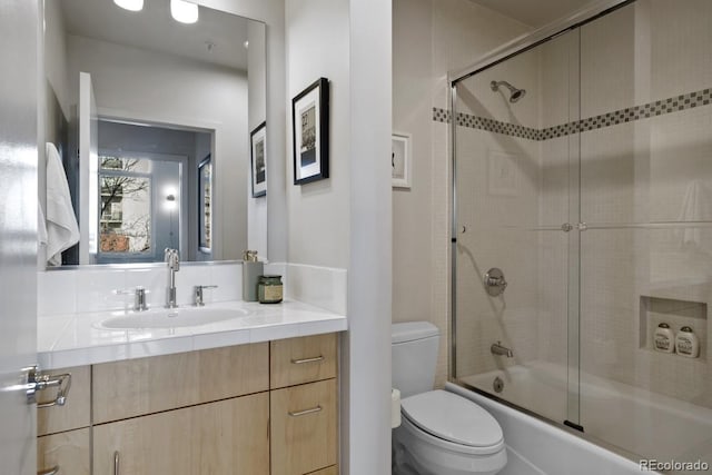 full bathroom with enclosed tub / shower combo, toilet, and vanity