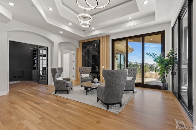 interior space with a chandelier, hardwood / wood-style floors, and a raised ceiling