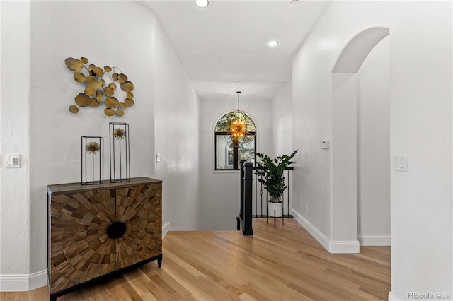 hallway with hardwood / wood-style flooring and an inviting chandelier