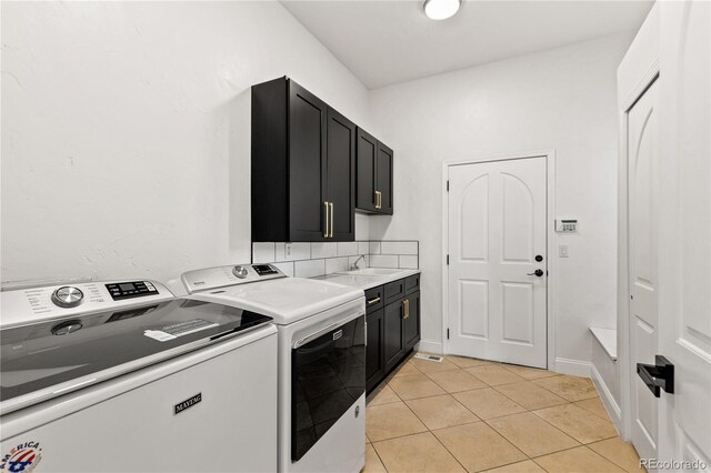 laundry area featuring cabinets, sink, light tile patterned flooring, and washing machine and clothes dryer