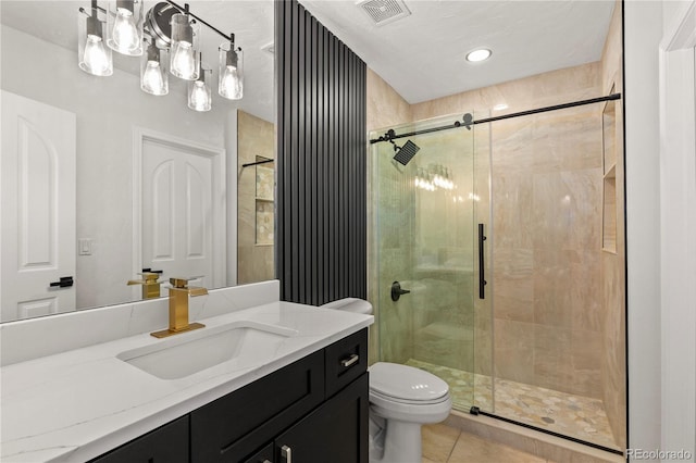 bathroom featuring tile patterned flooring, vanity, a shower with shower door, and toilet